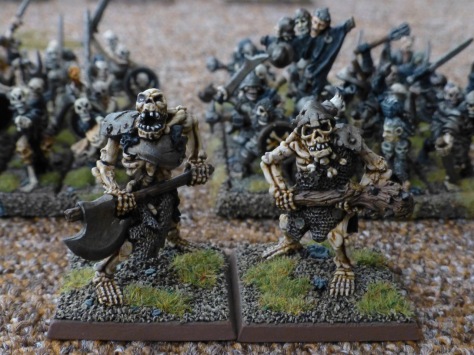 Two skeletal ogres standing in front of units of skeleton warriors