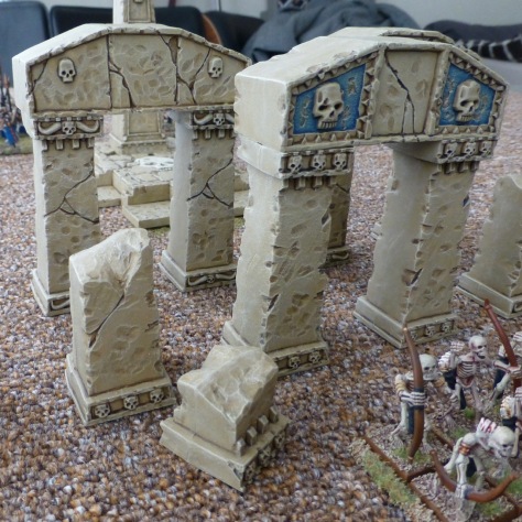 Broken columns and arches of sandstone with skeletal archers in front