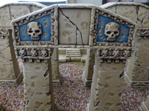 An arch of sandstone blocks decorated with carved skulls and with faded blue panels