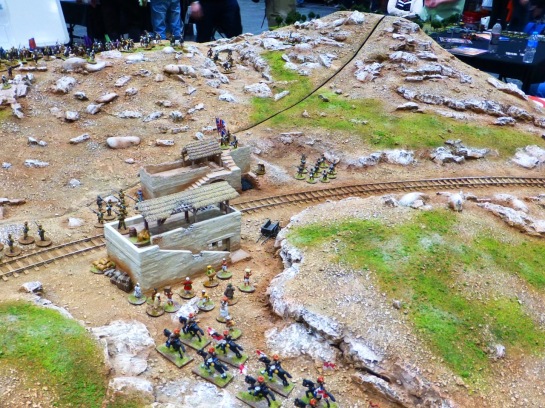 A railroad line and small station in a rocky landscape with scattered infantry and cavalry units