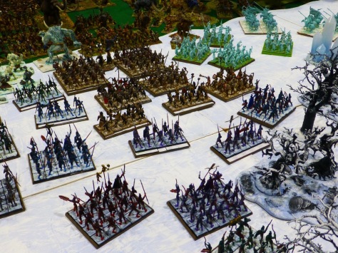 A snowy landscape with regiments of spearmen wearing dark armour, units of etherial troops and troll sized monsters