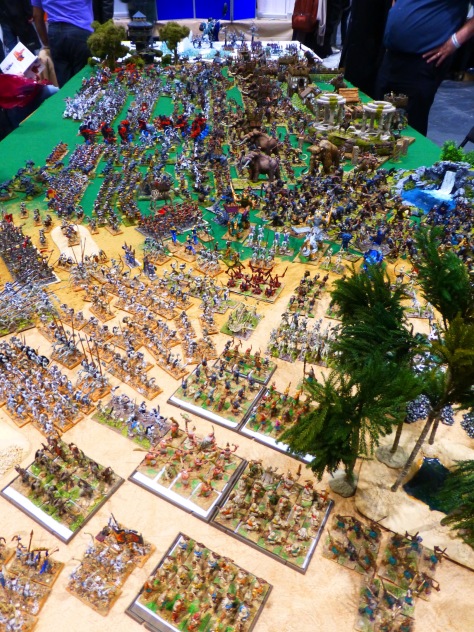 Large wargaming table with a transition from desert to ice landscapes and hundreds of miniatures packed in close formation 