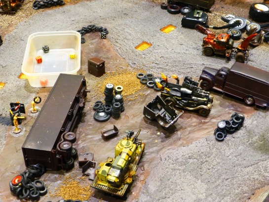 A muddy racing track with converted car models, tire stacks and wrecks