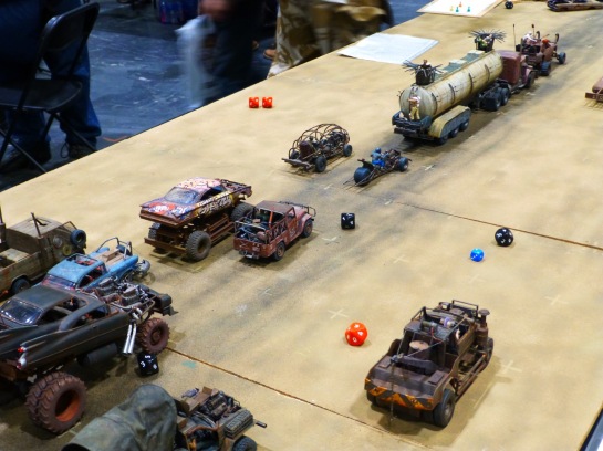 A desert gaming table with scale model cars converted in post-apocalyptic style