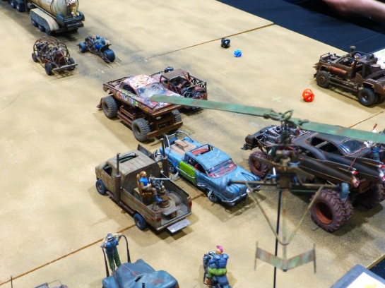 A gyrocopter hovering over models cars shown in pursuit of a tanker