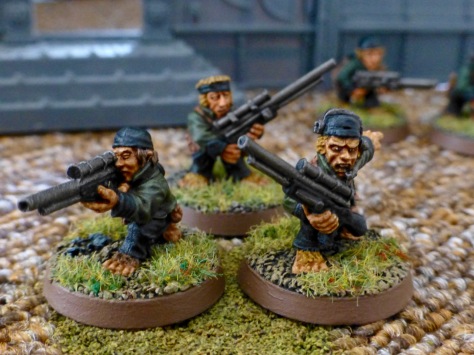 Group of three Halfling models wearing green uniform jackets and holding rifles