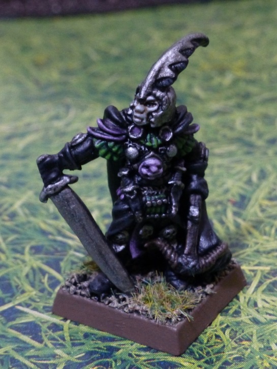 Miniature figure of a Dark Elf with black, purple, green and silver armour and clothing