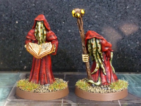 Two robed figures with a staff and grimoire