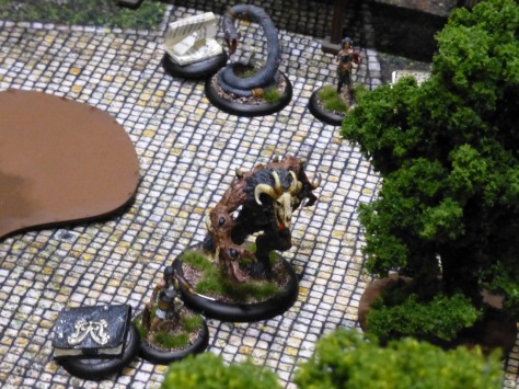 Large beastman, giant snake and human figures on a cobblestone square