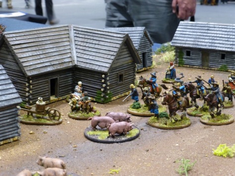 Troops moving through a hamlet with civilians and pigs