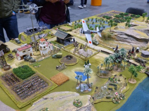 Wargames table with tropical terrain and fighter jets circling above