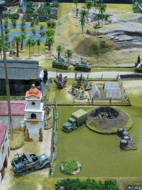 US vehicles and infantry on the outskirts of a small settlement