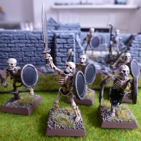 Skeletons with swords and shields emerging from a walled graveyard