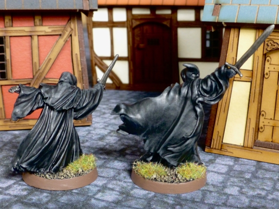 Two figures with black flowing robes from behind